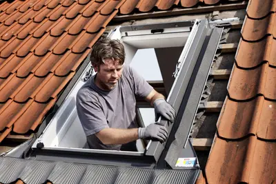 Monteur werkt aan een dakraam tussen de dakpannen