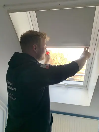Monteur van Dakraam Vervangservice stelt een VELUX rolgordijn af