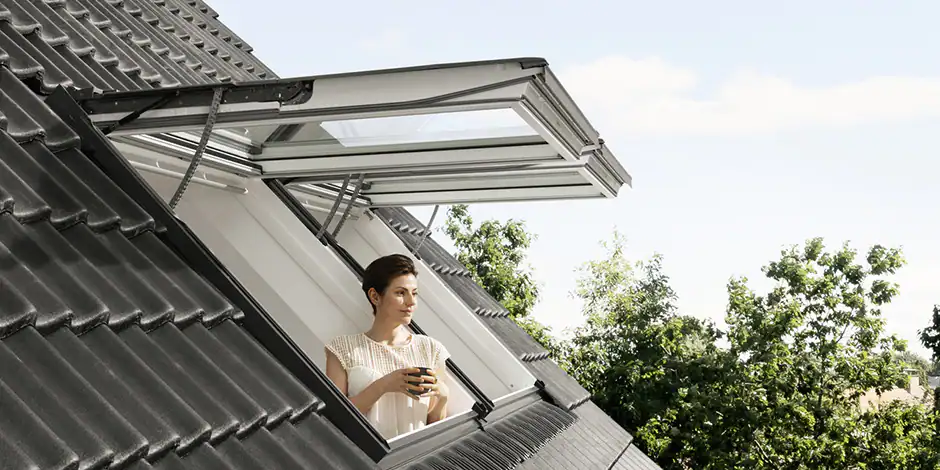 Vrouw kijkt uit een geopend VELUX uitzettuimelvenster